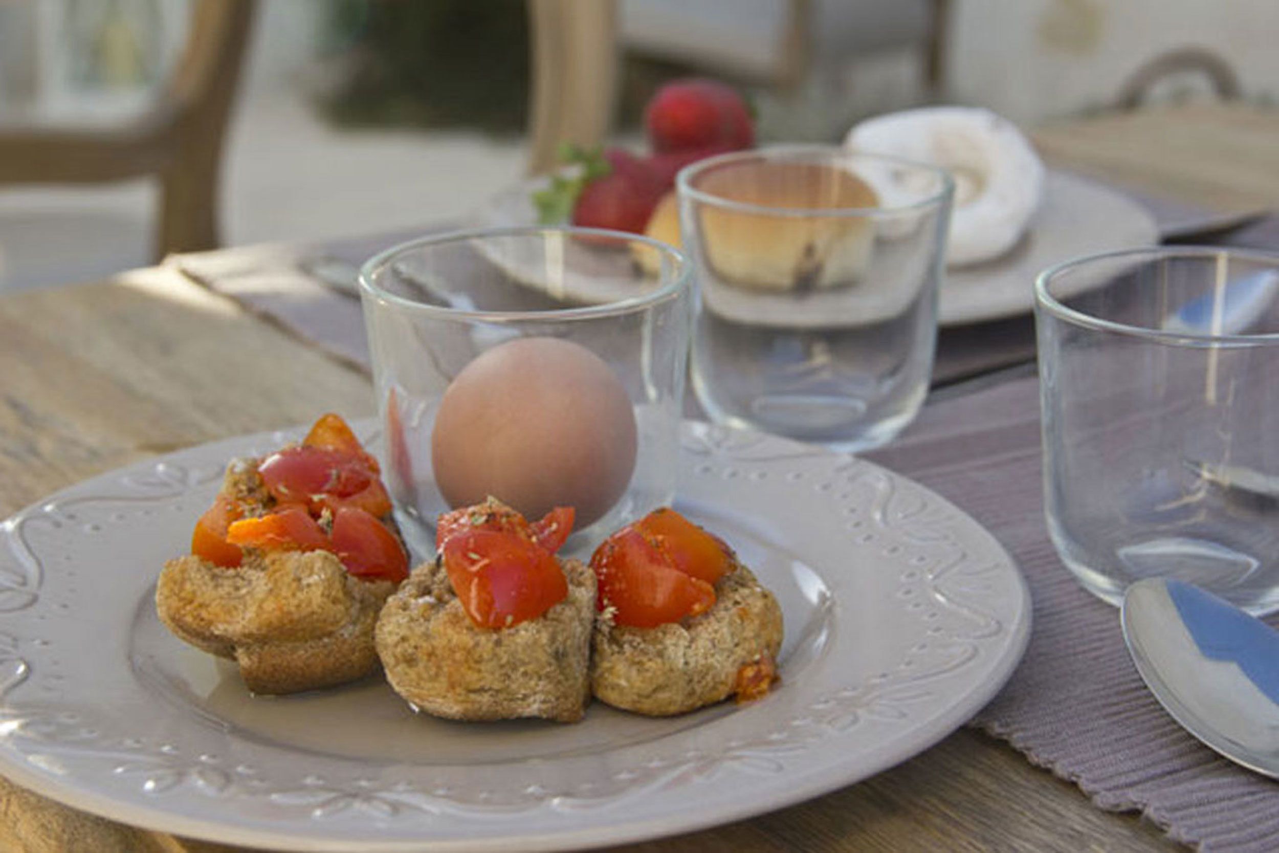 A plate with food items, a glass, and a spoon on a table.