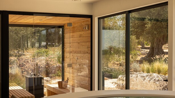 A modern spa area with a hot tub, wooden seating, and a view of a natural landscape through large windows. - Masseria San Francesco (Fasano)