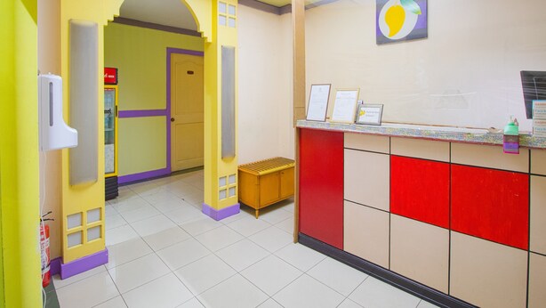 A brightly colored reception area with a tiled floor, a reception desk, and a wall-mounted sign. - OYO 790 Mango Inn (Manila)