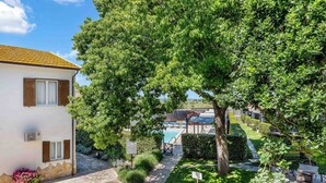 Una villa con piscina, rodeada de abundante vegetación y cielo despejado.
