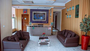 A reception area with a wooden reception desk, two brown sofas, a coffee table with magazines, and a large globe decoration on the wall.
