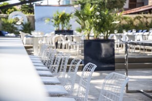 A row of white wireframe chairs and tables arranged outdoors, likely for dining or socializing. - Kalyon Çeşme (Cesme)