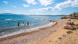 A beach with pebbles, clear water, and a few people. - Kalyon Çeşme (Cesme)