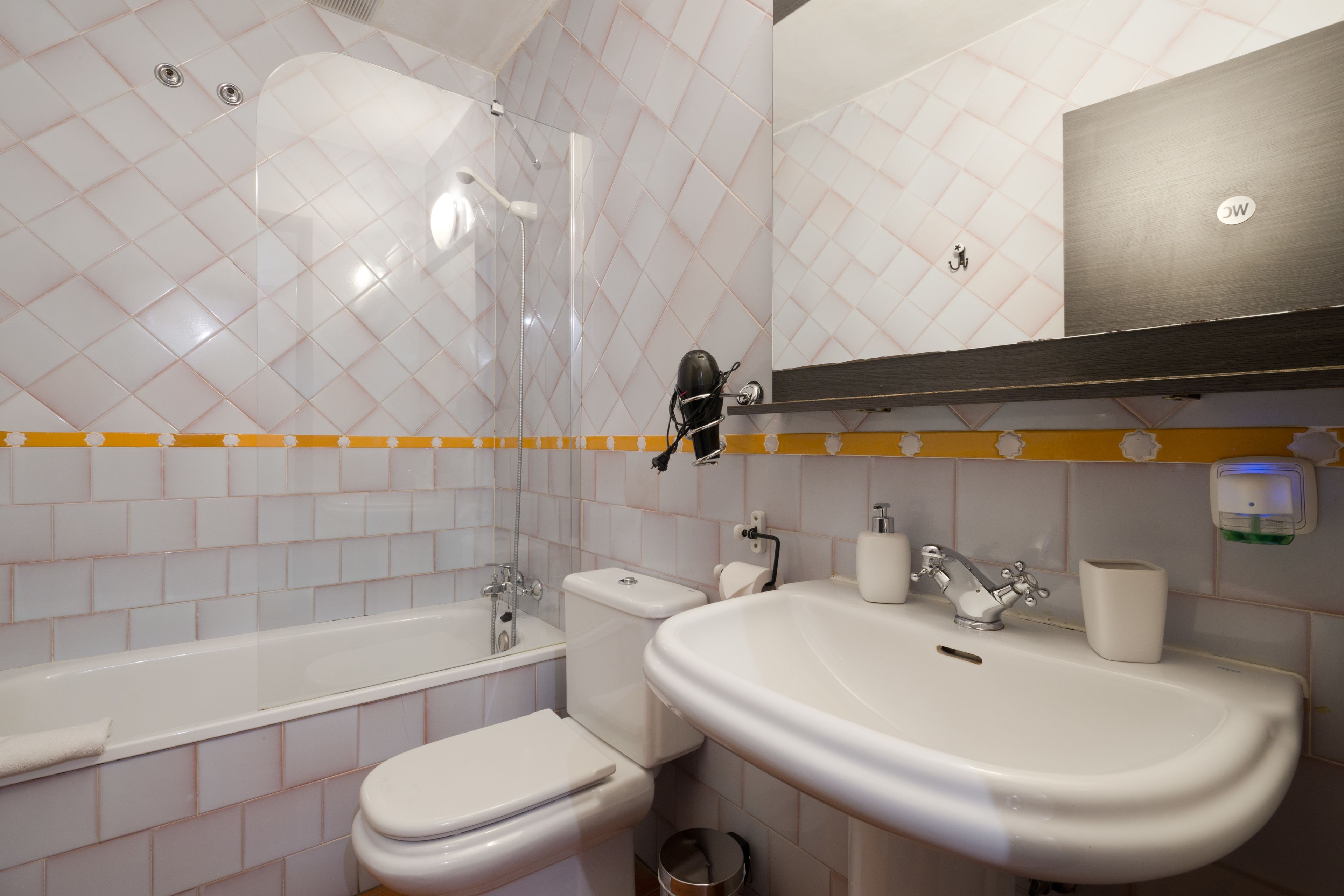 A bathroom with a bathtub, toilet, sink, and a mirror.