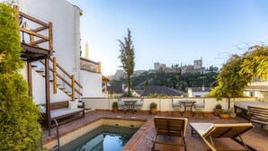 A rooftop pool area with a small pool, wooden deck, and outdoor furniture. - Casa Bombo (Granada)
