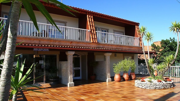 Un hotel con una recepción, un balcón con barandilla y plantas en macetas.