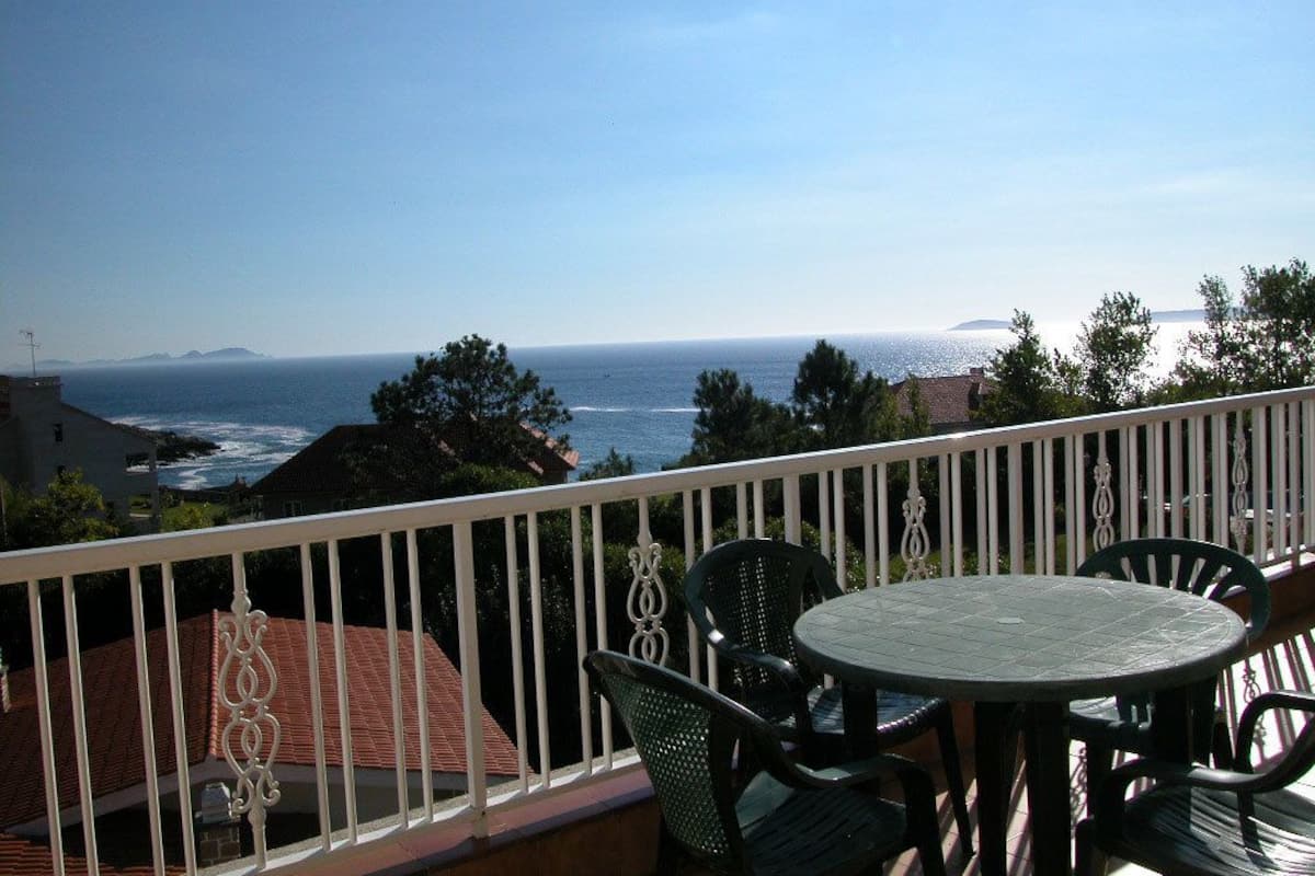 Un balcon avec vue sur l’océan, comprenant une table ronde et quatre chaises.