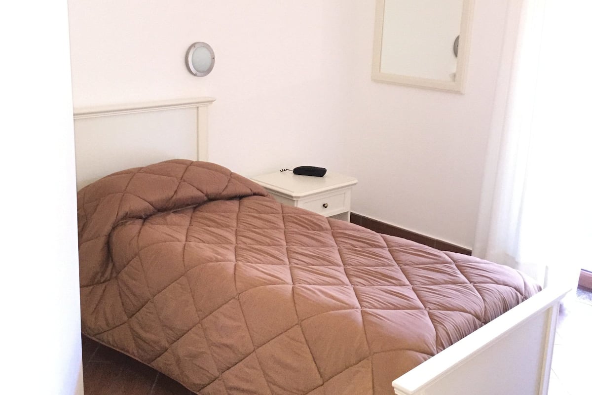 Une chambre à coucher avec un lit, une table de chevet, un miroir et une horloge murale.