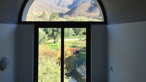 A room with a large arched window overlooking a mountainous landscape. - Hotel Giardino San Michele (Novi Velia)