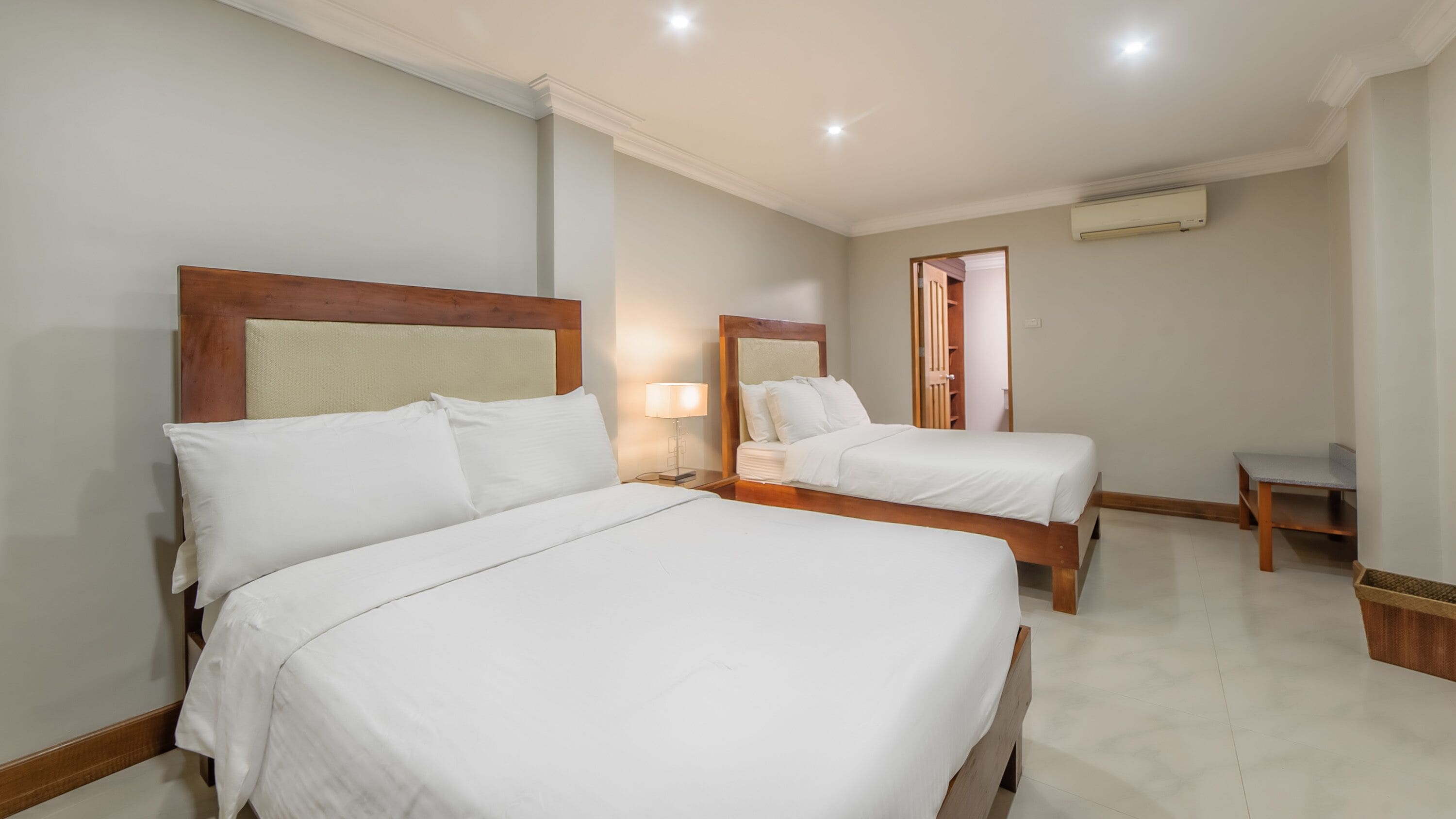 Una habitación de hotel con dos camas, una mesita y un espejo.