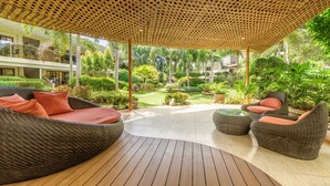 A covered outdoor seating area with wicker furniture and a glass-top table.