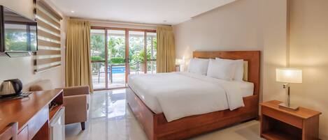 Habitación de hotel con cama, mesita de noche, lámpara, escritorio, silla y televisor.