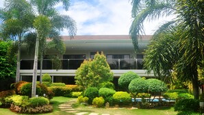 A building with a garden in front, including a pathway and various trees.