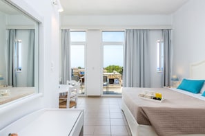 A hotel room with a bed, a desk, and a balcony with a table and chairs. - Aqua Marina (Rethymno)