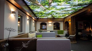 Un interior moderno con un techo que simula un dosel forestal, zonas de estar con cojines e iluminación ambiental.