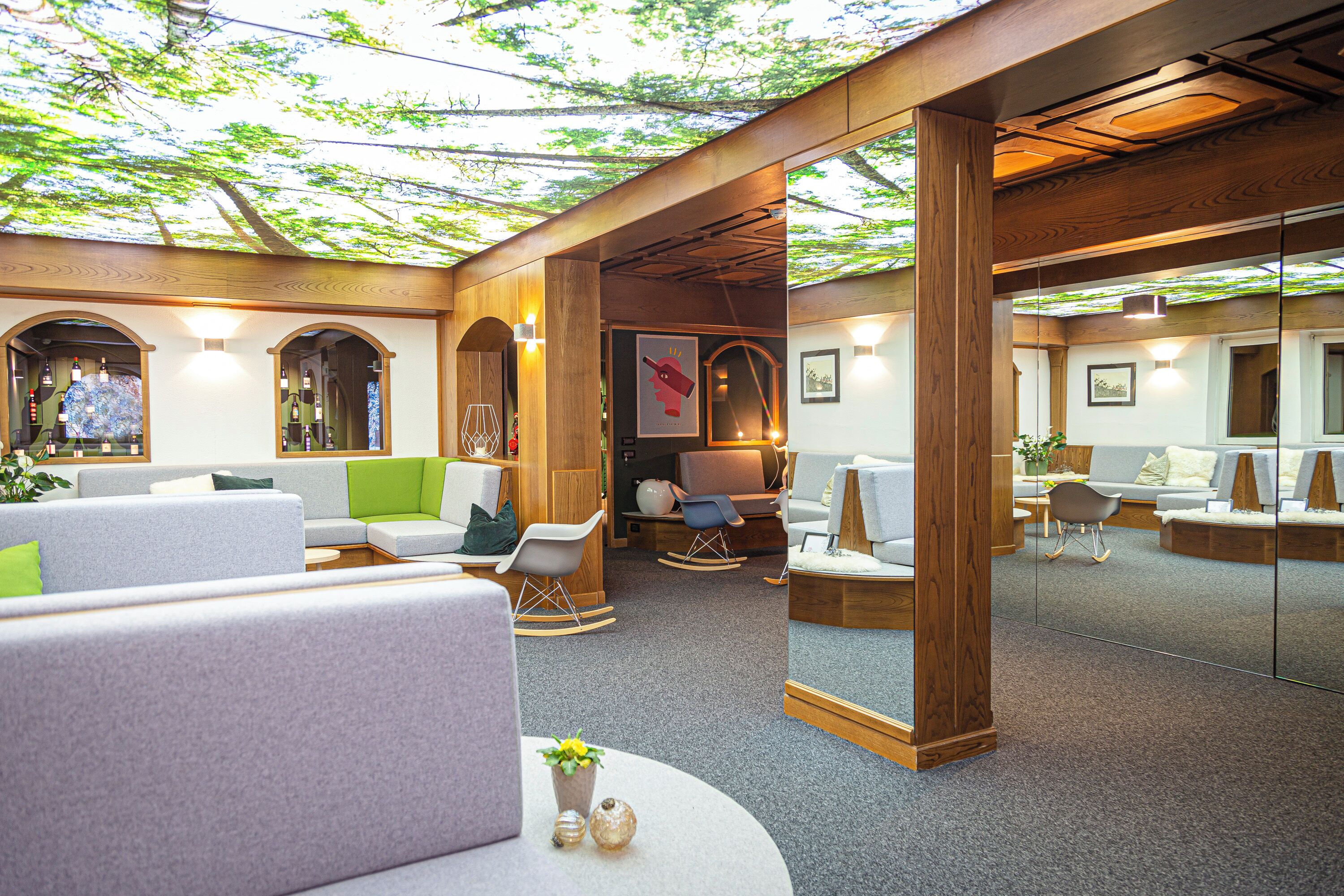 A modern lounge area with seating arrangements, wooden beams, and a large mirror reflecting the space.
