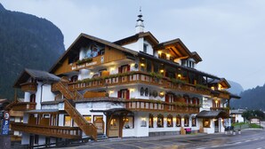 Un hotel de varios pisos con balcones de madera y un telón de fondo montañoso.
