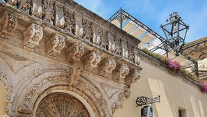An ornate stone archway with a wooden door, a small window, and a sign above it. - Relais Il Mignano (Nardò)