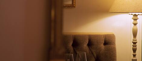 A dining table with two wine glasses and a fork, set against a wall with a mirror and a lamp.
