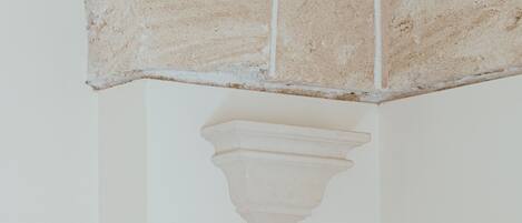 A corner of a room with a white wall and a section of exposed brickwork.