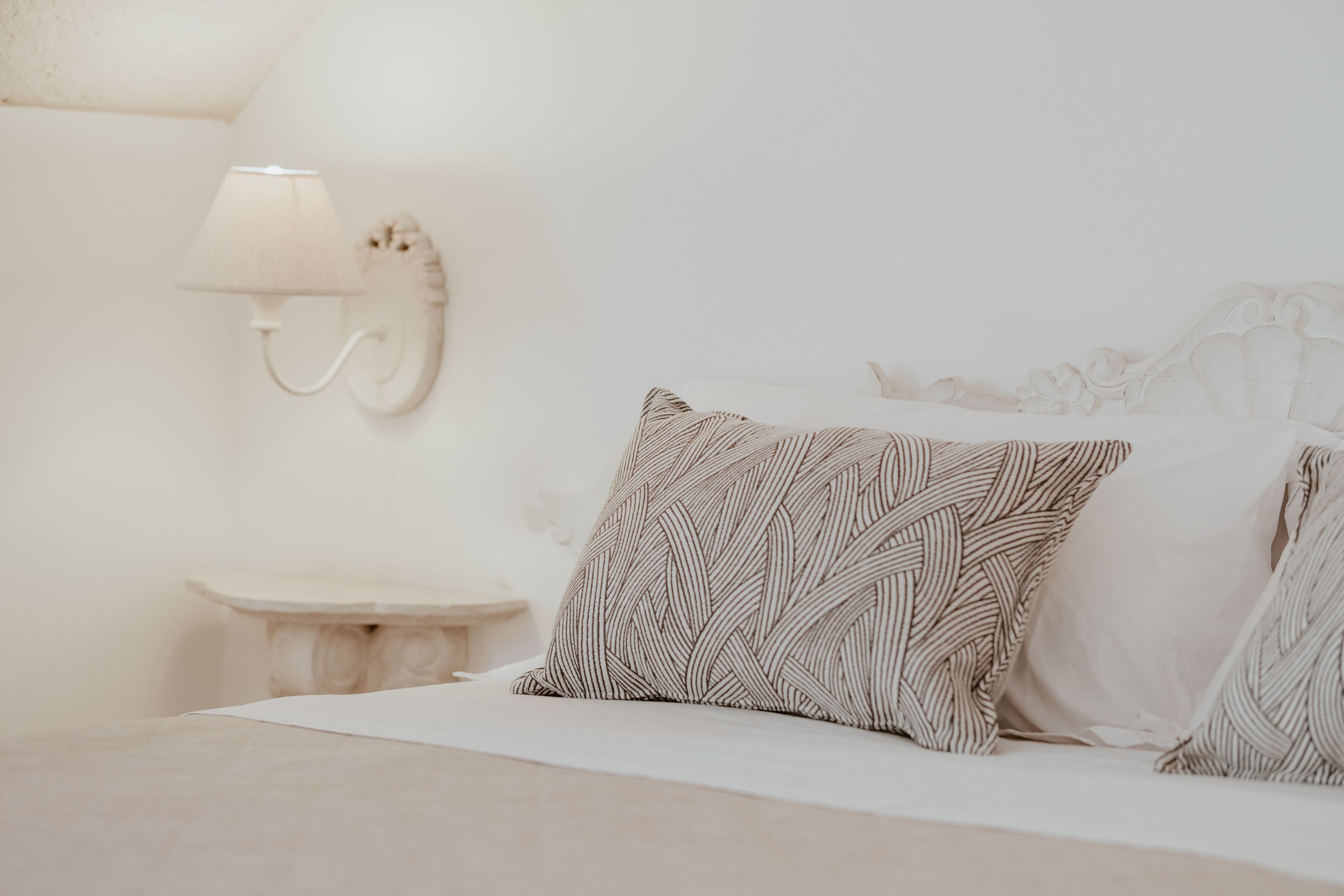 Een slaapkamer met een bed, een nachtkastje en een wandlamp.