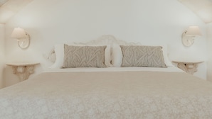 A bedroom with a large bed, two bedside lamps, and a small table. - Relais Il Mignano (Nardò)