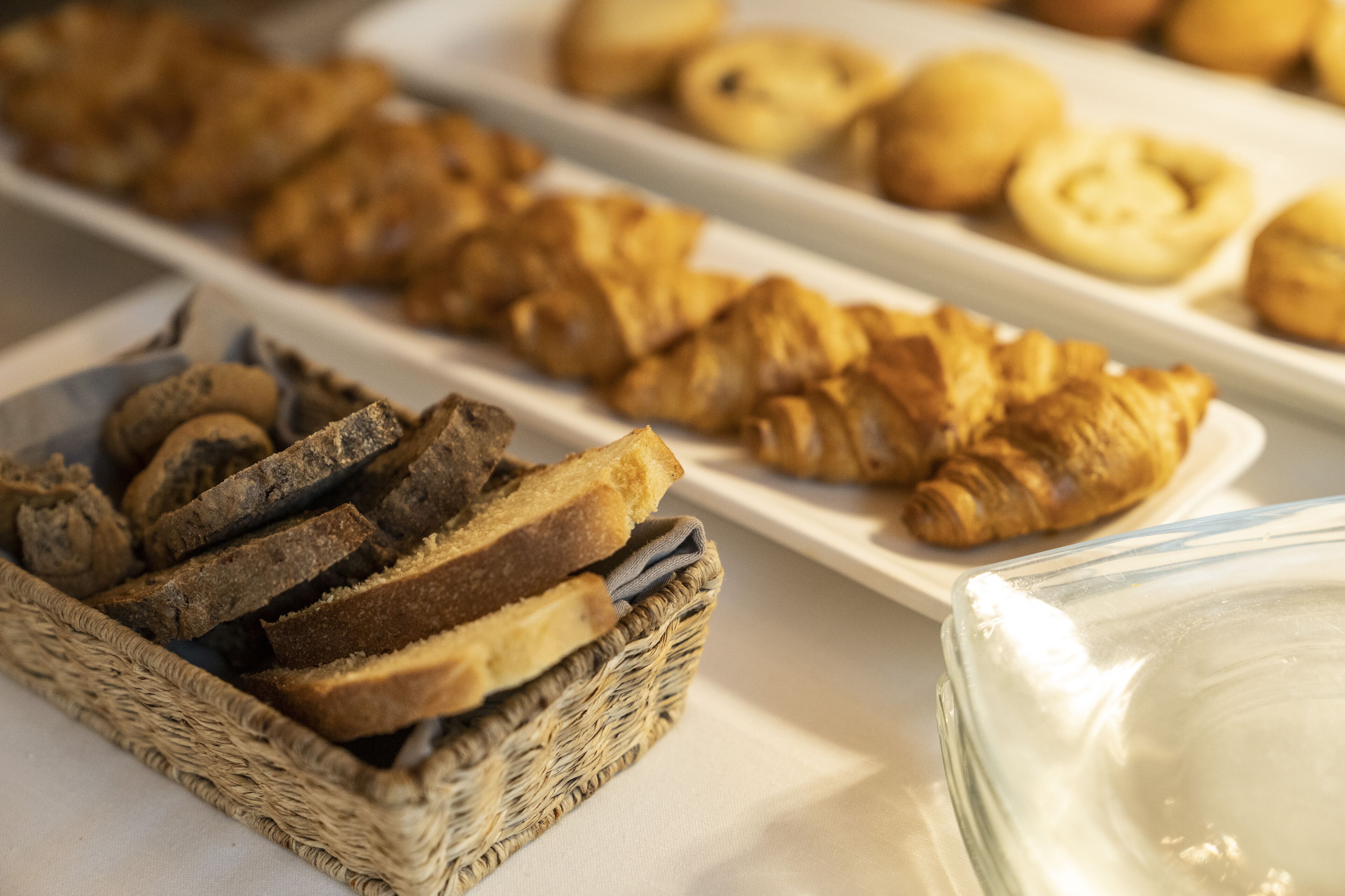 A buffet with various baked goods including bread, croissants, and pastries.