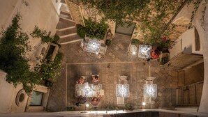 An outdoor terrace with multiple seating areas, stone walls, and hanging plants. - Relais Il Mignano (Nardò)