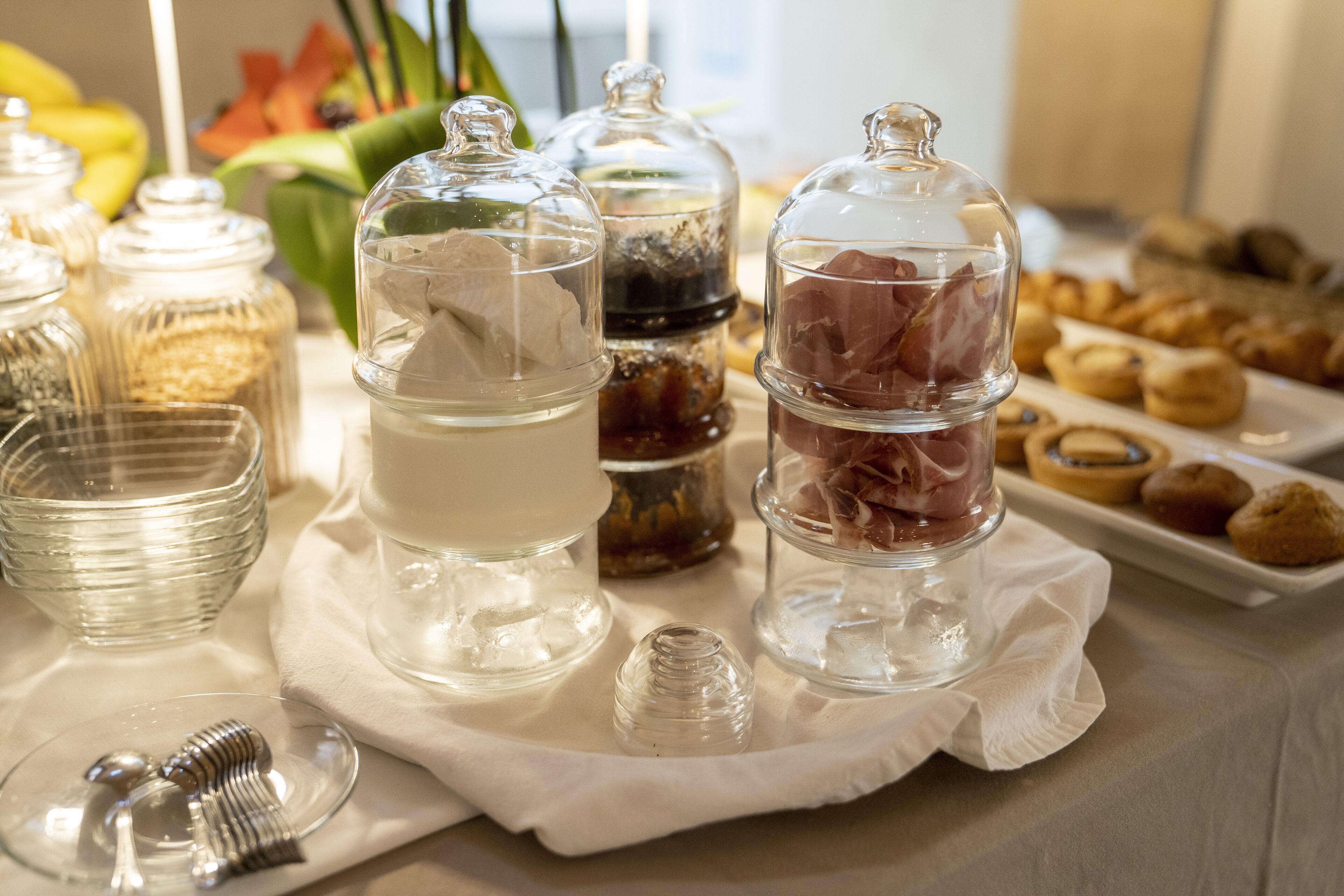 A buffet table with various food items and condiments in glass containers.