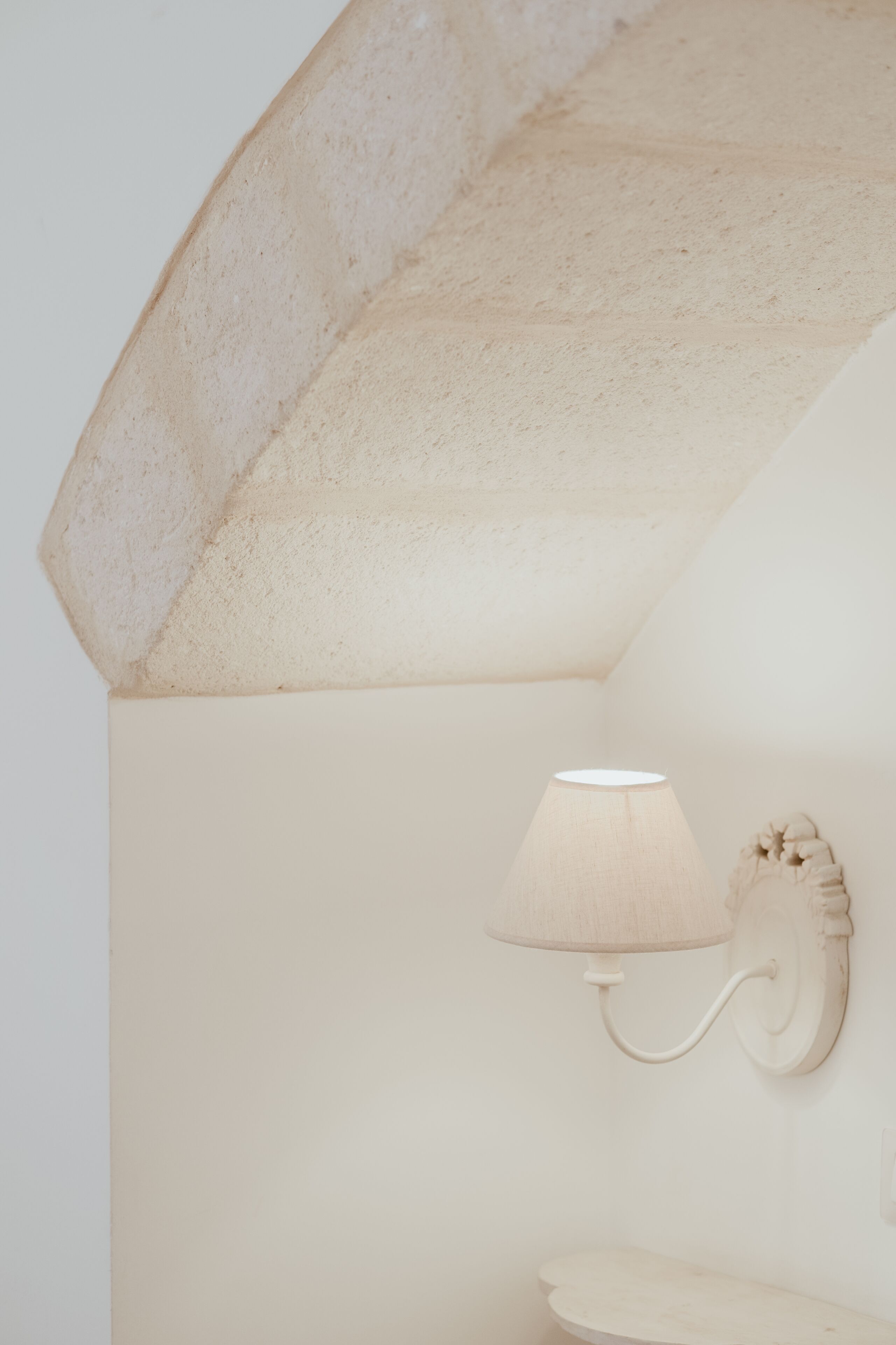 A bathroom with a white sink, a wall-mounted light fixture, and a textured ceiling.