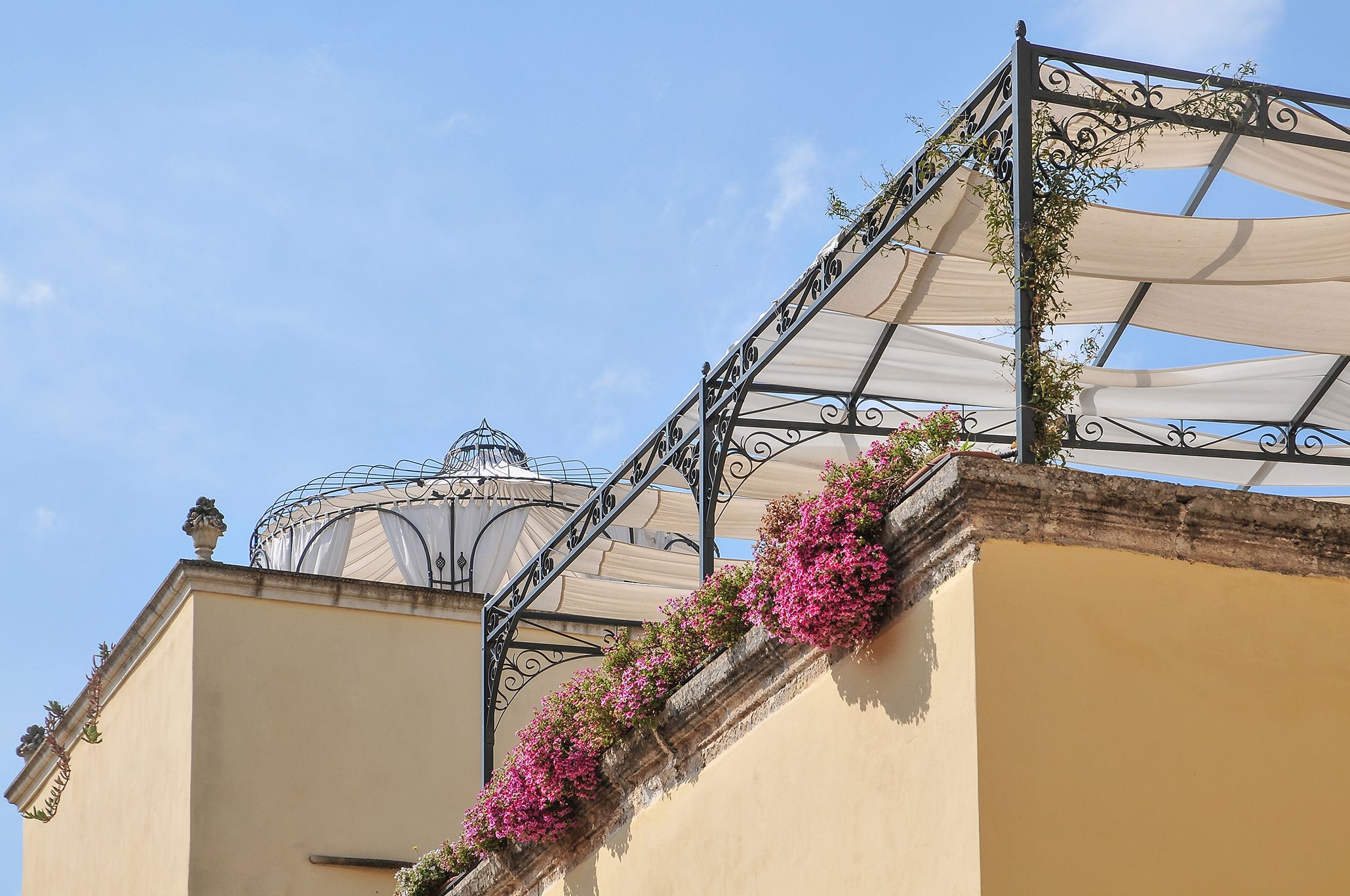 Un bâtiment doté d’un balcon orné de fleurs roses et d’une rampe en métal décorative.