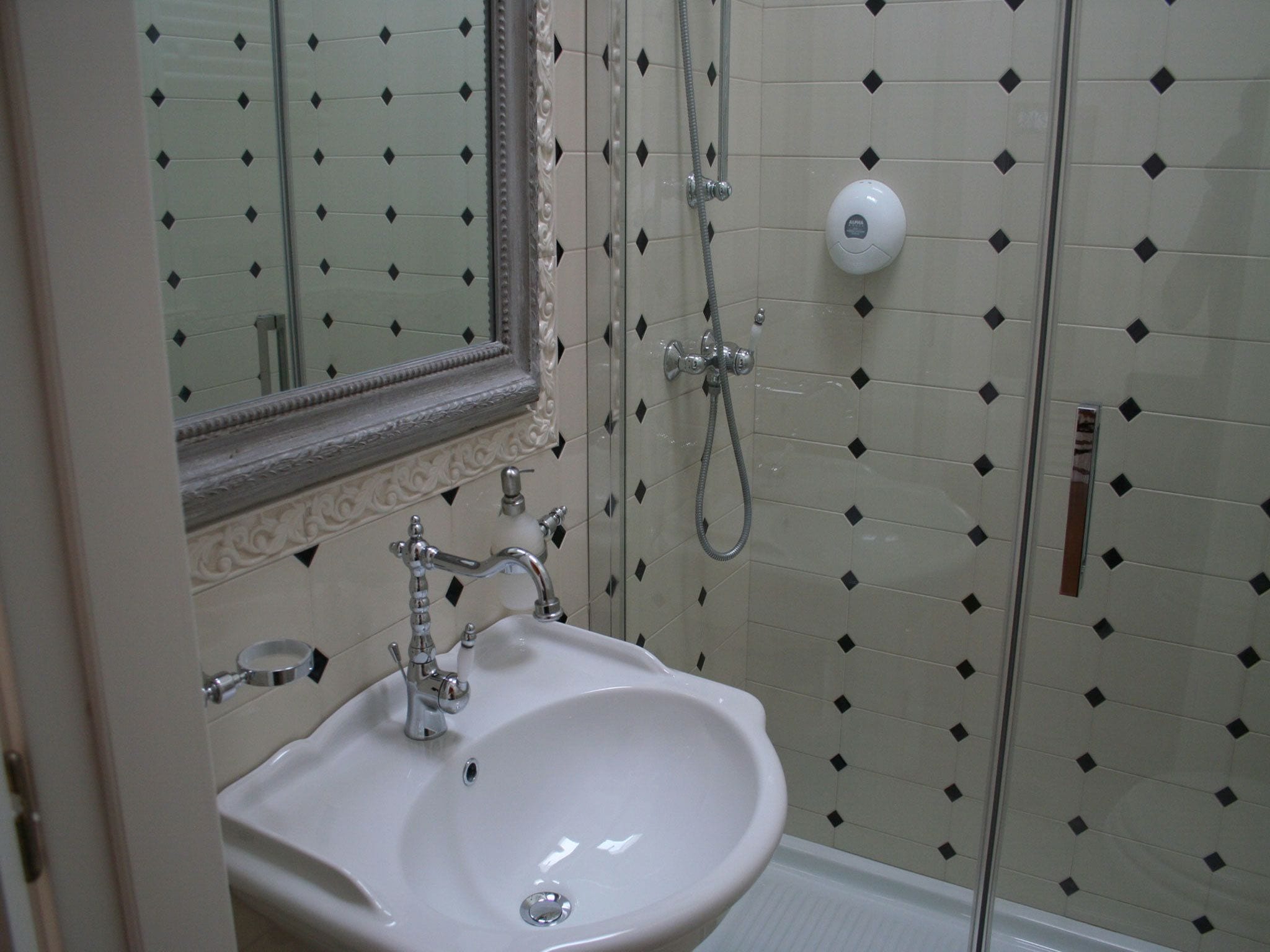 A bathroom with a white sink, a mirror, and a shower with a handheld showerhead.