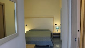 A narrow hallway leading to a bedroom with a bed, a nightstand, and a lamp. - Hotel Palinuro (Centola)