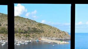 A view through a window of a coastal area with boats, a hilly landscape, and a clear sky. - Hotel Palinuro (Centola)