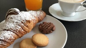 A plate with a pastry, a glass of orange juice, a cup of coffee, and two cookies. - B&B Tosca (Verona)