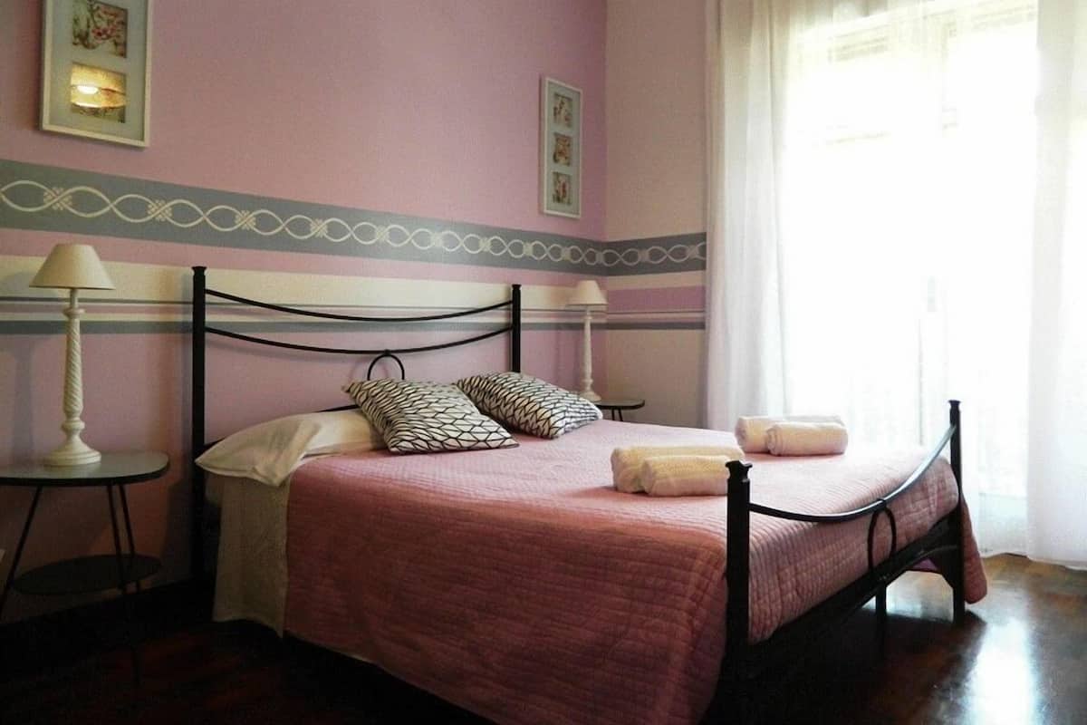 Un dormitorio con cama, almohadas, una mesita de noche y una lámpara.