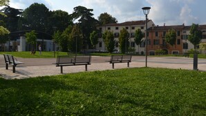 A park with benches, a paved walkway, and a building in the background. - B&B Tosca (Verona)