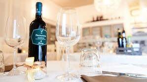 A table setting with a bottle of wine, glasses, and a candle. - CiCò Hotel (Carovigno)