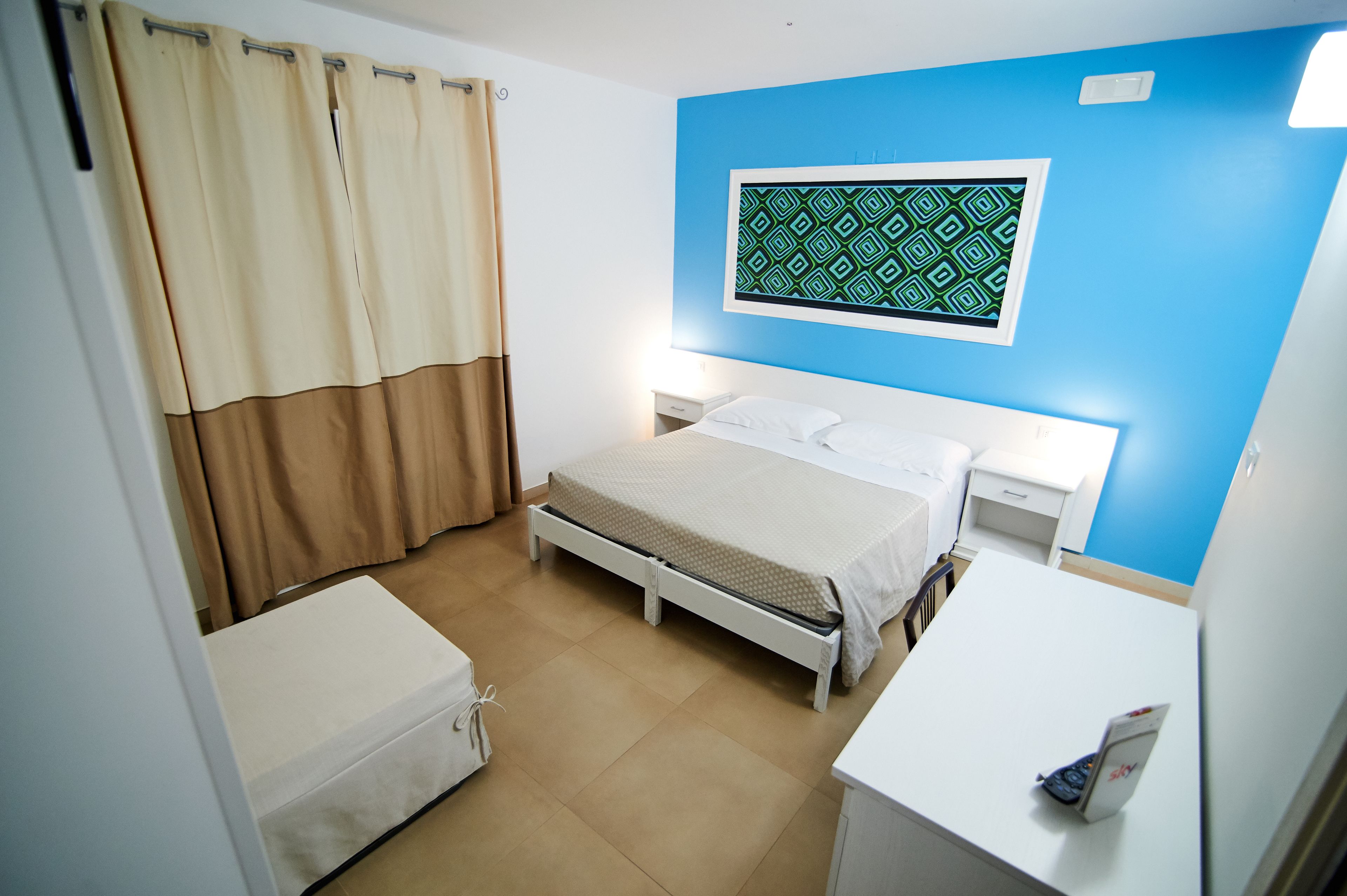 Un dormitorio con cama, mesitas de noche, escritorio y silla.