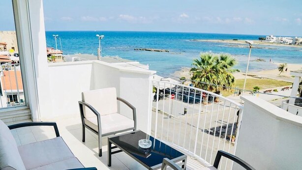 A balcony with a view of the sea, white furniture, and a small table. - CiCò Hotel (Carovigno)