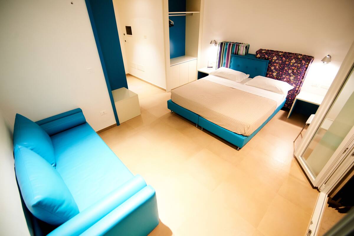 A room with a bed, a blue sofa, and a wardrobe.