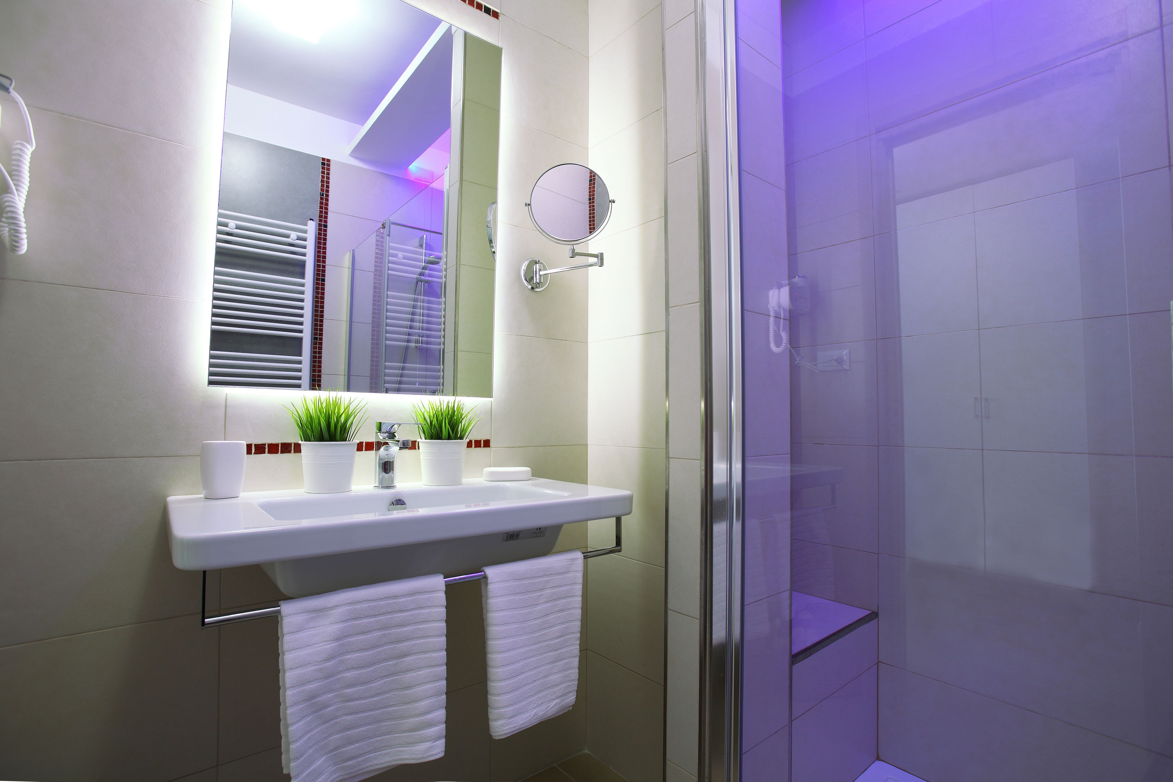 Un baño moderno con un lavabo blanco, espejo y perchero.