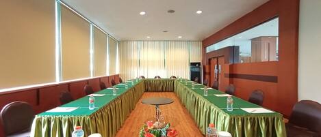 A conference room with a long table, chairs, water bottles, and a vase with flowers.
