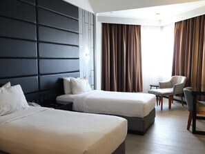 Quarto de hotel com duas camas, uma escrivaninha e uma cadeira.
