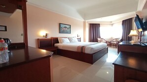 Una habitación de hotel con una cama, un escritorio, una silla, una lámpara y un cuadro en la pared.