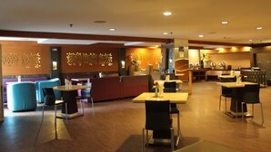 Un restaurante moderno con suelo de madera, asientos azules y morados, y una zona de cocina al fondo.