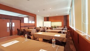 Un salón de conferencias con mesas dispuestas para reuniones, equipado con botellas de agua y blocs de notas.