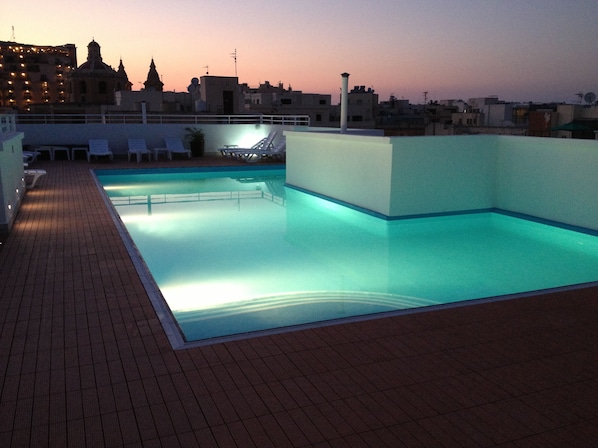 Una piscina al aire libre de temporada, sombrillas