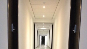 A long, narrow hallway with a shiny, reflective floor and doors on both sides. - Day's Inn Hotel and Residence (Sliema)