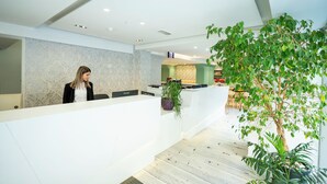 A modern reception area with a marble wall, a reception desk, and a potted plant. - Day's Inn Hotel and Residence (Sliema)